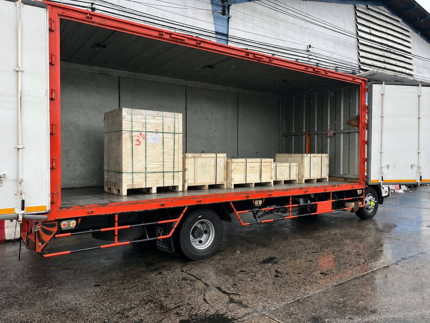Industrial chain delivery - red curtain truck loaded with crated shipment